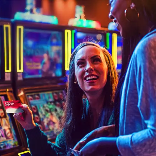 Woman showcasing a ONE club card at a slot machine